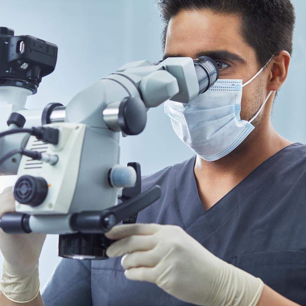 Ein medizinischer Fachangestellter schaut durch ein Mikroskop