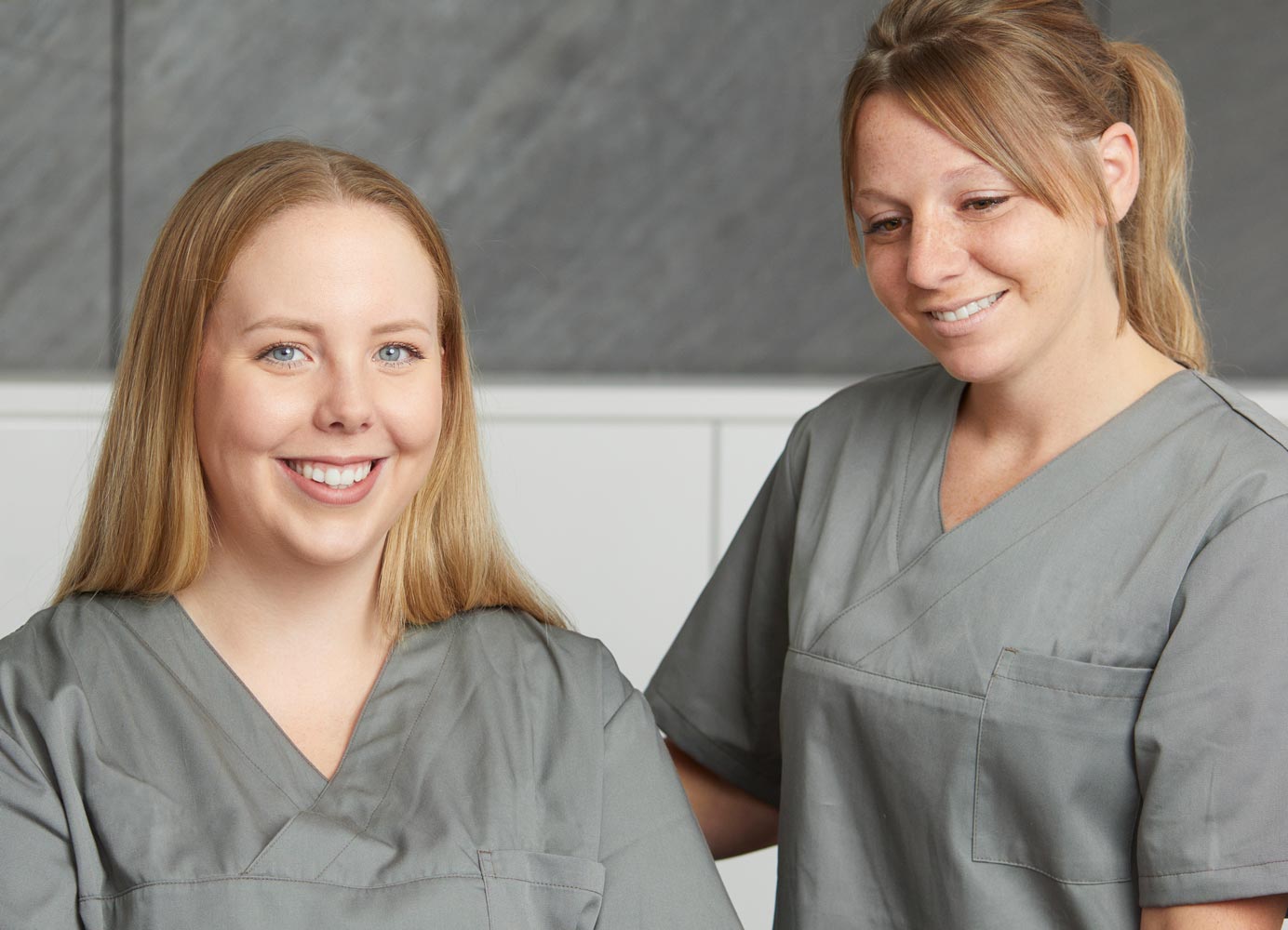 Zwei zahnmedizinische Fachangestellte in grauer Kleidung